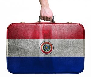 Tourist hand holding vintage leather travel bag with flag of Paraguay